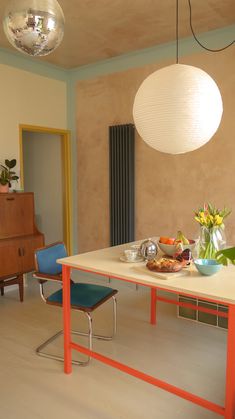 a dining room table with two chairs and a bowl of fruit on the table next to it