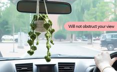 a person driving a car with a stuffed animal hanging from the dash