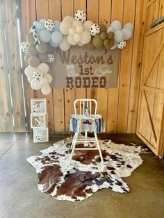 a white chair sitting on top of a cowhide rug in front of a wooden wall