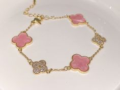 a pink heart bracelet on a white plate with gold chains and hearts in the middle