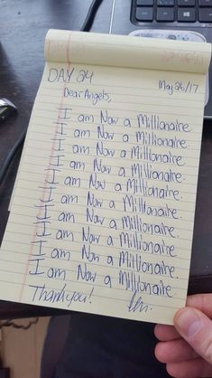 someone is holding up a piece of paper with writing on it that says i am now a millionaire