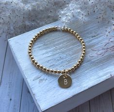 THIS ITEM SHIPS FOR FREE! Introducing the Classic Initial Charm Bracelet. This bracelet is made with 4mm gold-filled beads and a classic hand-stamped initial. The charm measures 1/2". Please review all of the photographs to see how the charm compares in size to a dime. This is the perfect way to add a  little something to your gold-filled bead bracelet.  I now have 2 fonts available in upper case only. If you have a preference, please indicate Font #1 or #2 in the personalization box. Otherwise, Gold Minimalist Stretch Bracelet As Gift, Minimalist Gold Stretch Bracelet For Gift, Gold Stretch Bracelet With Gold Beads As Gift, Gold Stretch Bracelet With Gold Beads For Gift, Dainty Gold Stretch Bracelet As Gift, Classic Gold Jewelry With Letter Beads, Elegant Charm Bracelet With Letter And Round Beads, Gold Charm Bracelet With Spacer And Round Beads, Elegant Gold Charm Bracelet With Letter Beads