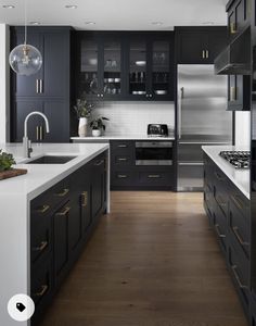 a modern kitchen with black cabinets and white counter tops, gold pulls on the handles