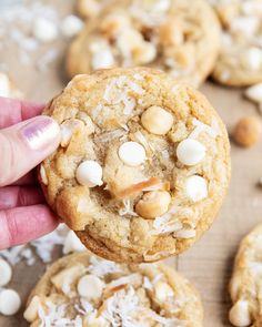 a person holding up a cookie with white chocolate chips