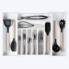 an assortment of kitchen utensils and spoons in a white box with dividers