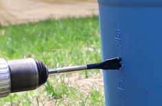 an electric drill is being used on a blue barrel