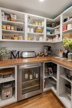 a kitchen with white cupboards and wooden counter tops, filled with food items on shelves