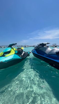 two jet skis in the water near each other on a clear blue sky day