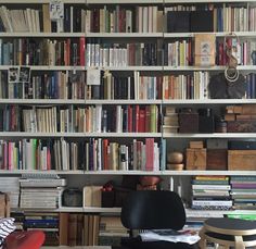 a bookshelf filled with lots of books next to a chair and table in front of it