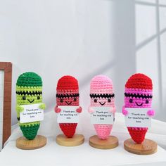 three small crocheted dolls with thank you notes on them, each holding a different type of item