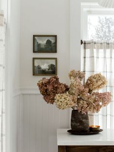 a vase filled with flowers sitting on top of a white table next to a window