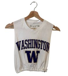 Vintage College Crop Tank Shop our vintage crop tanks that vary from a range of different graphics and colors All items you see are unique and the only one available in our shop Items fit true to size All items have been cut and altered into a crop tee All items are pre-worn, recycled, well kept items that are perfect for game days, college gatherings, every day wear, and more! If you have any questions about fit or the items, please send me a message before purchase. reworked adjustable drawstr Collegiate Sleeveless Top For Streetwear, Cotton Graphic Print Crop Top For Sports, Collegiate Sleeveless Tops With Letter Print, Retro Tank Tops With Letter Print, Retro Letter Print Tank Top For Streetwear, Retro White Tank Top For Streetwear, White Graphic Print Sports Crop Top, White Graphic Print Crop Top For Sports, Retro Crew Neck Tank Top With Letter Print