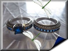 two silver rings with blue and white stones are on a shiny surface, surrounded by butterflies