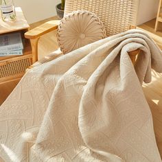 a white blanket sitting on top of a wooden chair next to a table and chairs