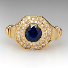 The JoAnne Mulhall designed ring is centered with one (1) round mixed cut natural sapphire set into a bezel and surrounded by a double tiered halo. The inner halo is accented with twenty (20), bead set, round brilliant cut diamonds. The outer halo is accented with twenty (20), bead set, round brilliant cut diamonds. The shank is accented with three (3), bezel set, round brilliant cut diamonds. The ring measures 13.9mm at the top, rises 7.0mm above the finger, tapering to 4.5mm wide and 3.3mm thick at the base of the shank. We offer complimentary ring sizing to fit. Formal Sapphire Ring With Halo, Formal 14k Gold Sapphire Ring With Halo Design, Formal Sapphire Halo Ring With Diamonds, Sapphire Halo Ring For Formal Events With Round Cut, Formal Sapphire Halo Ring With Round Cut, Timeless Sapphire Ring With Halo Setting, Heirloom Sapphire Halo Ring With Halo Setting, Sapphire Ring In Yellow Gold With Halo Setting, Luxury Halo Ring With Bezel Setting For Formal Occasions