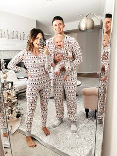 a man and woman in matching pajamas are taking a selfie while holding their baby