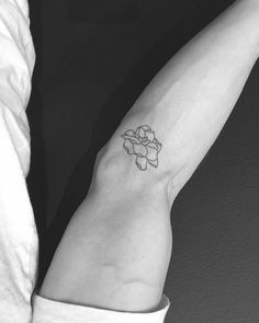 a black and white photo of a woman's arm with a flower tattoo on it