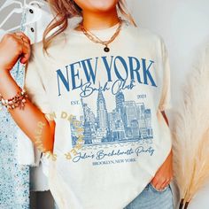 a young woman is smiling and posing in front of her clothing rack wearing a new york t - shirt