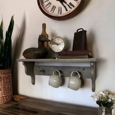 there is a clock on the wall above some coffee cups and watering can's