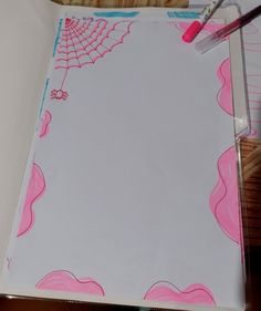 a white paper with pink and blue designs on it, next to a pair of scissors