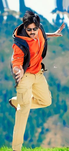 a man in an orange shirt and khaki pants is jumping with his arms outstretched