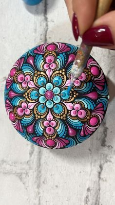 a woman is painting a colorful object on the floor with red nail varnishing