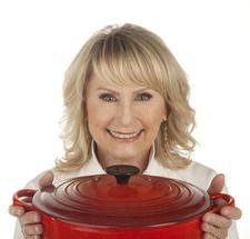 a woman holding a large red pot with a black lid on it's side