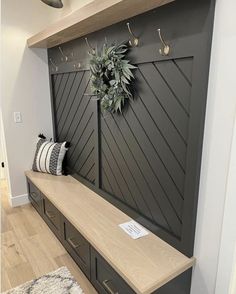 a wooden bench sitting in front of a wall with a wreath on top of it