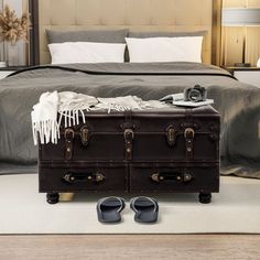 an old trunk is sitting on the floor in front of a bed