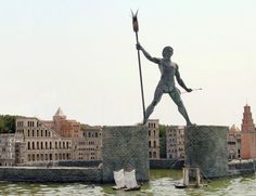 a statue of a man holding a spear on top of a bridge