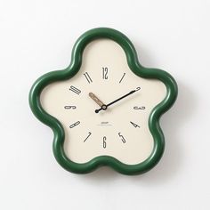 a green and white clock with numbers on the face against a white background that looks like an ornament