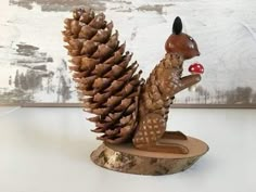 a figurine of a squirrel with a mushroom in its mouth sitting next to a pine cone