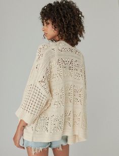 a woman is wearing a white sweater with crochet on the shoulders and back