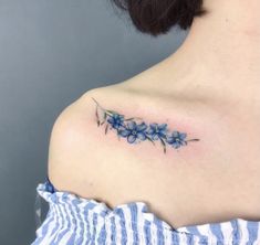 a woman's shoulder tattoo with blue flowers on the left side of her upper arm