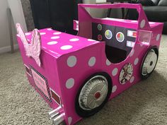 a pink car made out of cardboard sitting on the floor