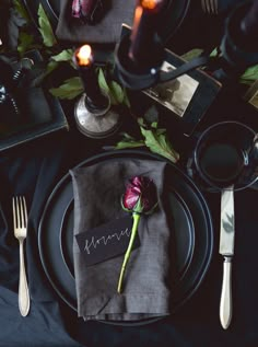 a place setting with flowers, candles and menus on the table for dinner party