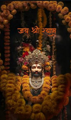 an idol is surrounded by flowers and garlands in front of a sign that reads,