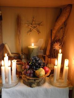 a table topped with candles and fruit on top of it