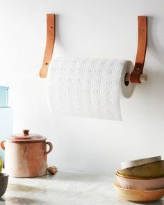 a white wall with two wooden hooks on it and some dishes in front of it