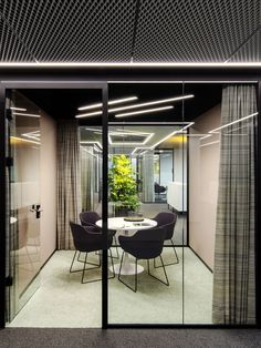 an office meeting room with glass walls and round table surrounded by chairs in the middle