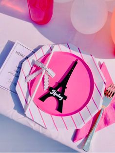 a pink plate with the eiffel tower on it is next to a fork and knife