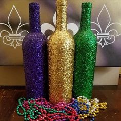 three glitter bottles are sitting on a table next to some beaded beads and a fleur de lis sign