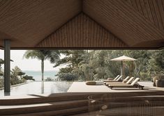 an outdoor swimming pool with chaise lounges overlooking the water and palm trees in the background