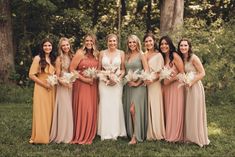 a group of women standing next to each other in front of some trees and grass