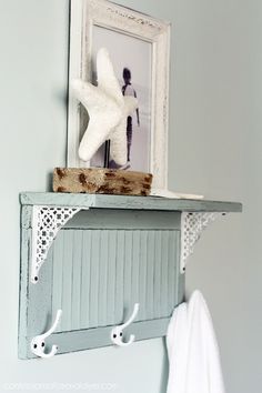 a white starfish is on top of a shelf above a towel rack in a bathroom