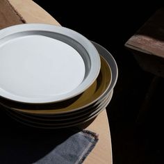 a stack of white and gold plates sitting on top of a wooden table next to each other