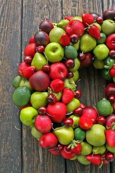 a wreath made out of apples, pears and other fruit on a wooden surface