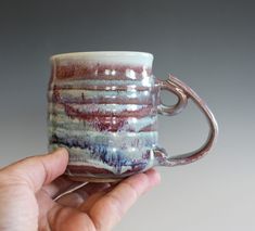 a hand holding a coffee cup with an artistic design