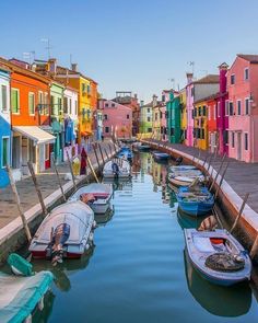 several boats are docked in the water next to some buildings and colorfully painted houses