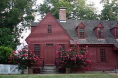 a red house with pink flowers in the front yard